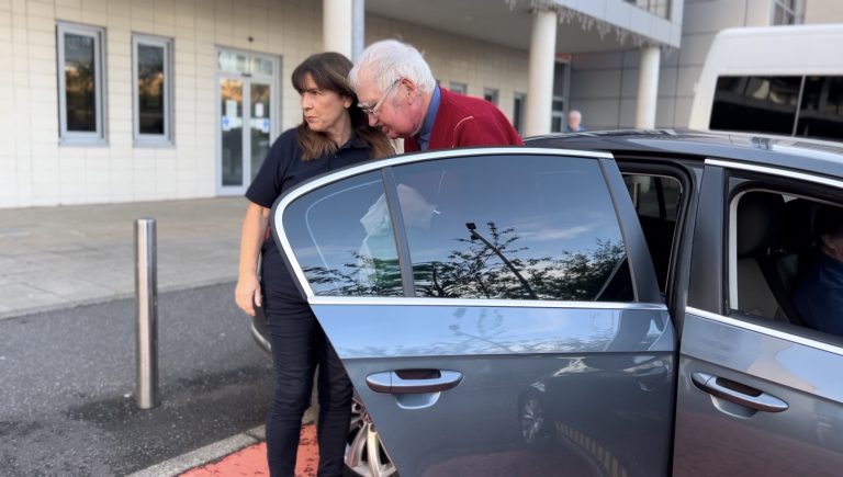 Volunteer helping a patient out of a car to their appointment.